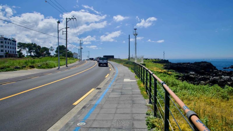 Curving coastal road and blue bike lane beside Eoyeong Park.