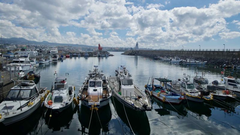 Boats rest in Iho Port near horse-shaped lighthouses.