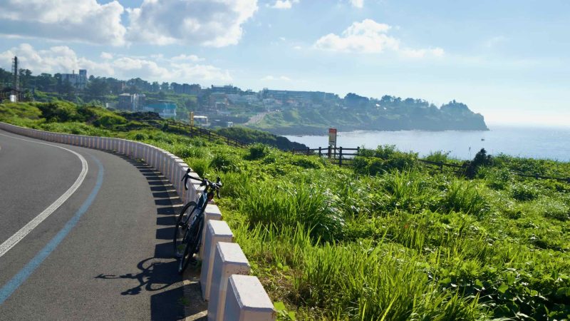 Road bike paused along the Hagu-Aewol Coastal Road above the bay.