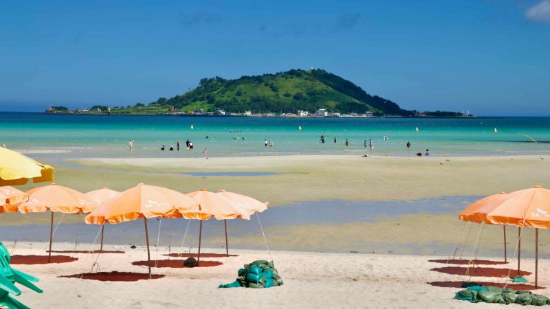Orange parasols at Hyeopjae with Biyangdo Island beyond.
