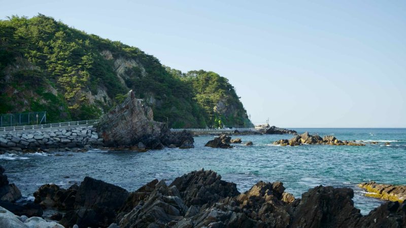 A view of Heonhwa Road with a prominent rock jutting out from the East Sea beside the road.
