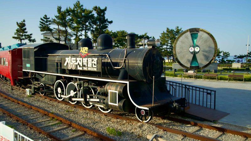 A historic steam locomotive is on display at the Jeongdongjin Time Museum, accompanied by the 40-ton hourglass.
