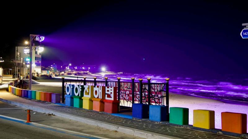 The colorful Ayajin Beach sign stands brightly along the road.