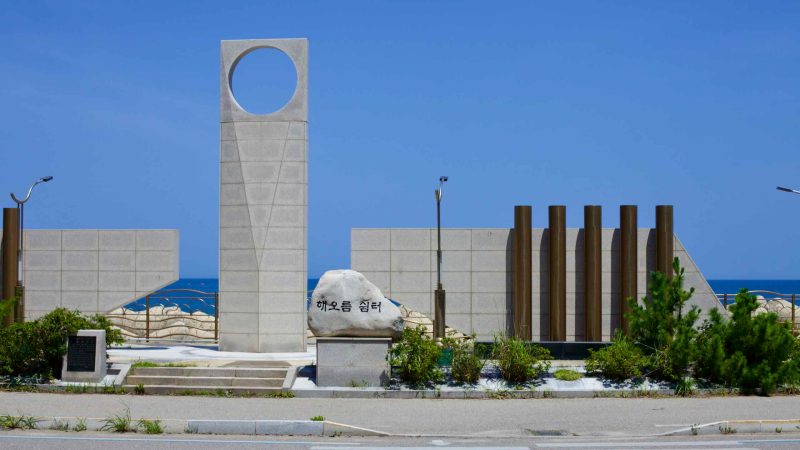 The Haeoreum Rest Area near Geojin Port features a monument with ten pillars and a central tower, symbolizing the unity of Goseong's coastal communities.