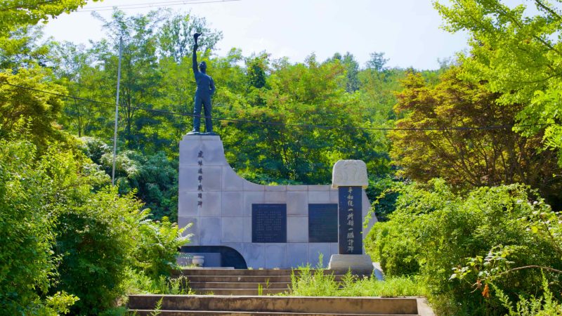 At the Goseong Unification Observatory, a statue stands on a granite pedestal, depicting a man holding a torch aloft, symbolizing hope for the reunification of Korea.