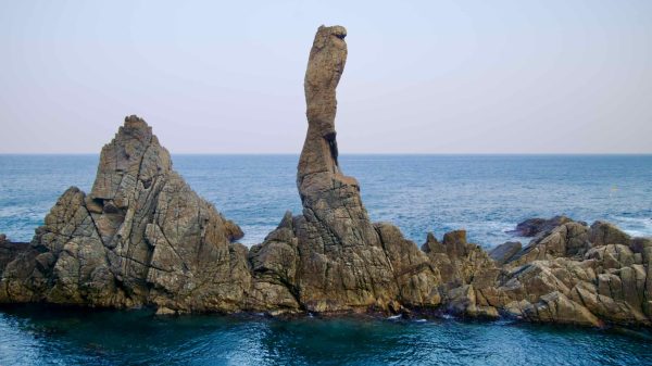 From a viewing platform on the Chogok Yonggul Cave Hiking Trail, the Candlestick Rock stands tall and thin, protruding from the East Sea surrounded by other rocks.