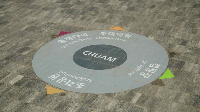 A directional sign on the pavement in Chuam, guiding visitors to various attractions including Candlestick Rock.