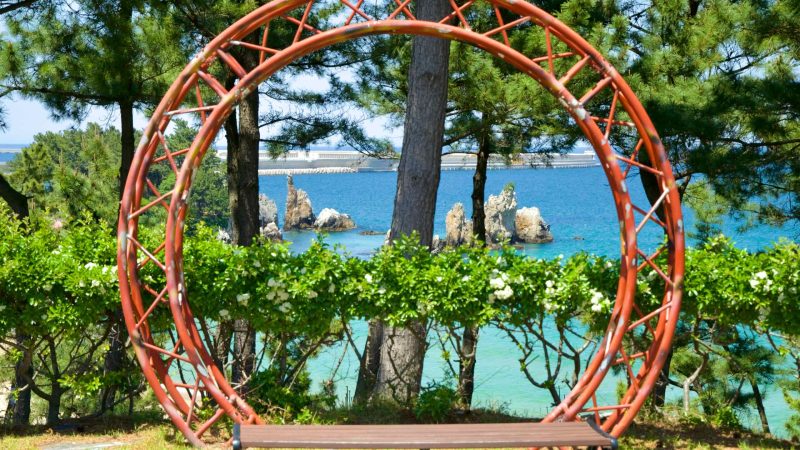 A circular frame overlooks the iconic Chuam Candlestick Rock, framed by lush greenery and the turquoise waters of the East Sea.