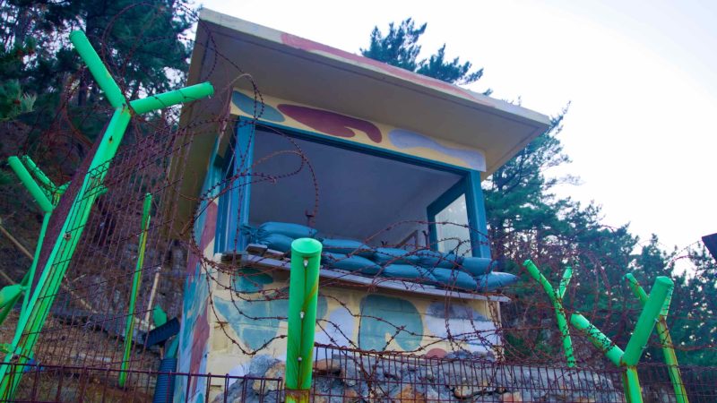Facing the sea, a decommissioned military lookout outpost, surrounded by barbed wire, stands as a small concrete hut on the Chogok Yonggul Cave Hiking Trail.