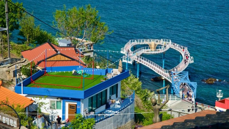 A view of the skywalk over the East Sea from Nongoldam Street, with colorful rooftops and lush greenery.
