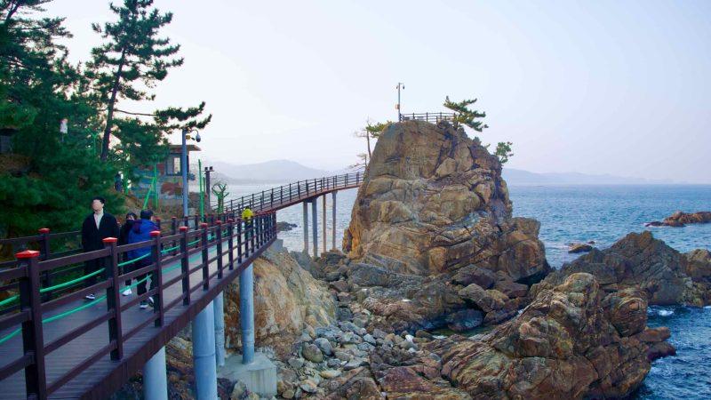 A view along the Chogok Yonggul Cave Hiking Trail, with a walking deck in the foreground, a tall rock observatory in the midground, and the East Sea in the background.