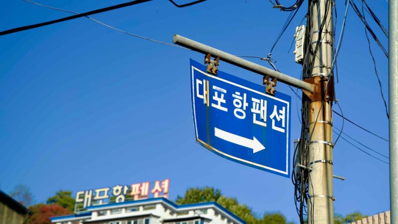 A blue directional sign points towards the Daepo Port Observatory, guiding visitors to the scenic lookout point near Sokcho’s famous fishing port.
