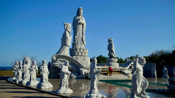 The towering Avalokitesvara statue, surrounded by intricately carved guardian statues, stands as a centerpiece at Huyuam Hermitage near the East Sea coast.