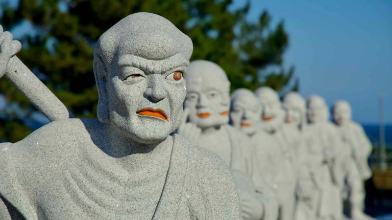 A row of intricately carved Bodhisattva statues near the Avalokiteśvara statue, reflecting Buddhist artistry and devotion.