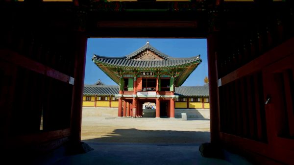 A framed view of Binilru Pavilion at Naksansa Temple, as seen through the ornate Four Heavenly Kings Gate, highlighting traditional Korean architecture.