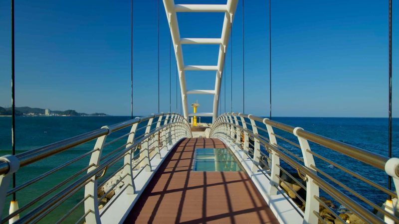 A glass-floor panel highlights the center of the white arched bridge at Namae Sunrise Observatory, offering breathtaking views of the East Sea below.