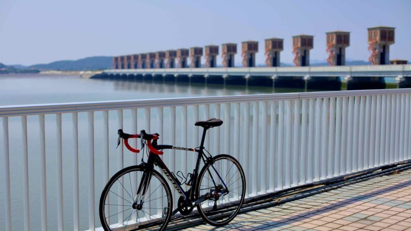 A road bicycle leans against a railing at the Geum River Estuary Bank.