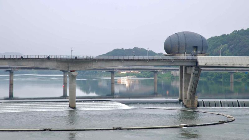 The westernmost control tower of Ipo Weir stands over calm waters, where stepped spillways and mirrored reflections mark the South Han River’s tranquil flow.