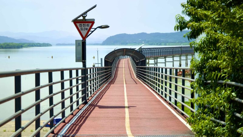 A picture of a raised cycling path that leads to Gangjeong Goryeong Weir (강정고령보) along the Nakdong River in Daegu, South Korea.