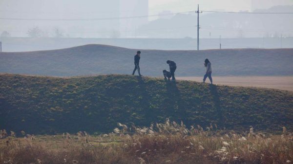 Visitors walks along the grassy embankments of Jeongbukdong Toseong Fortress.
