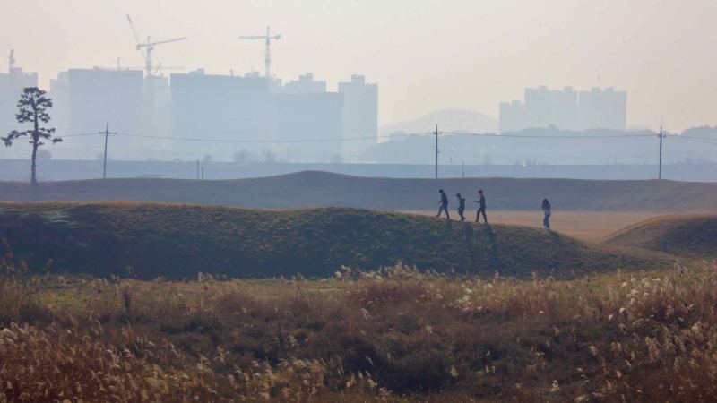 Visitors walk along the grassy earthen walls of Jeongbukdong Toseong Fortress.