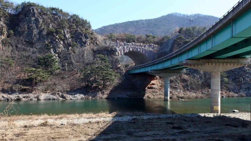 A picture of a roadway bridge passing through a rocky face in the Jinnamgyoban Area in Mungyeong City, South Korea.
